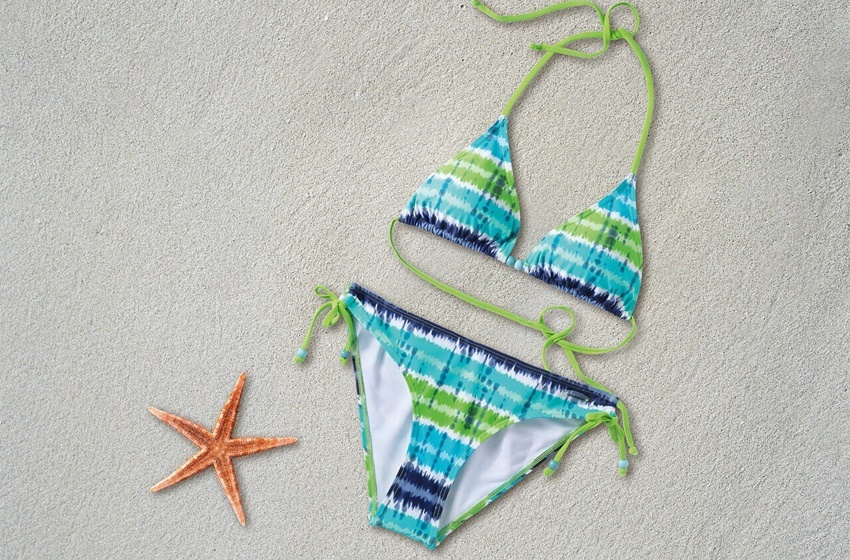 Ženski kupaći kostim zeleno plave boje, na pesku