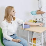 Žena sedi na stolici u laboratoriji, priprema se za vadjenje krvi.
