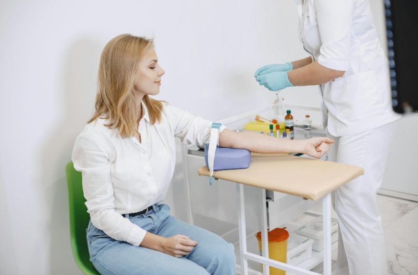 Žena sedi na stolici u laboratoriji, priprema se za vadjenje krvi.