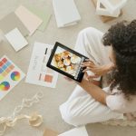 Devojka sedi na podu i gleda nešto na tabletu