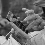 Osoba leži na kauču i koristi telefon