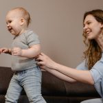 Majka drži dete dok hoda po kauču