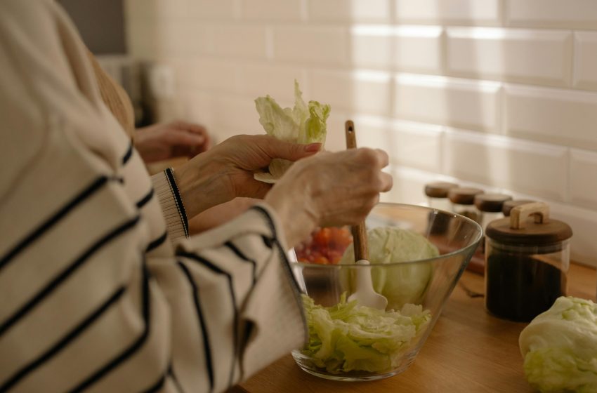 Ruke stavljaju listove zelene salate u staklenu činiju.