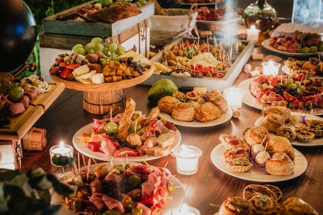 Raznovrsni ketering poslušžen na stolu, okružen svećama.