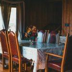 Trpezarijski sto sa crvenim kožnim stolicama i cvetnim aranžmanom