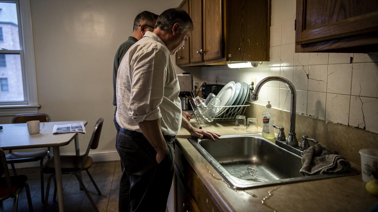 Dva muškarca stoje pored sudopere i gledaju mokru radnu površinu