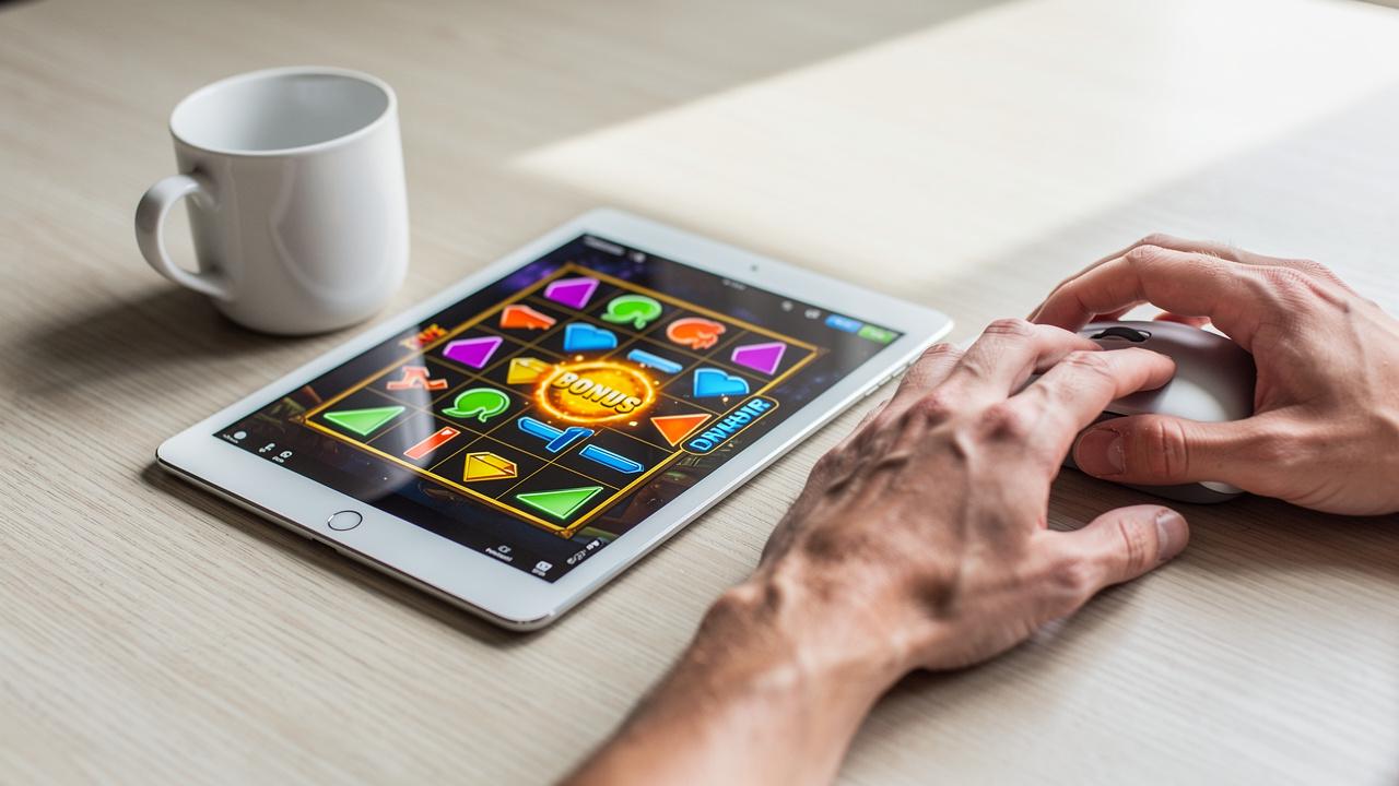 Muškarac gleda u tablet sa slotovima