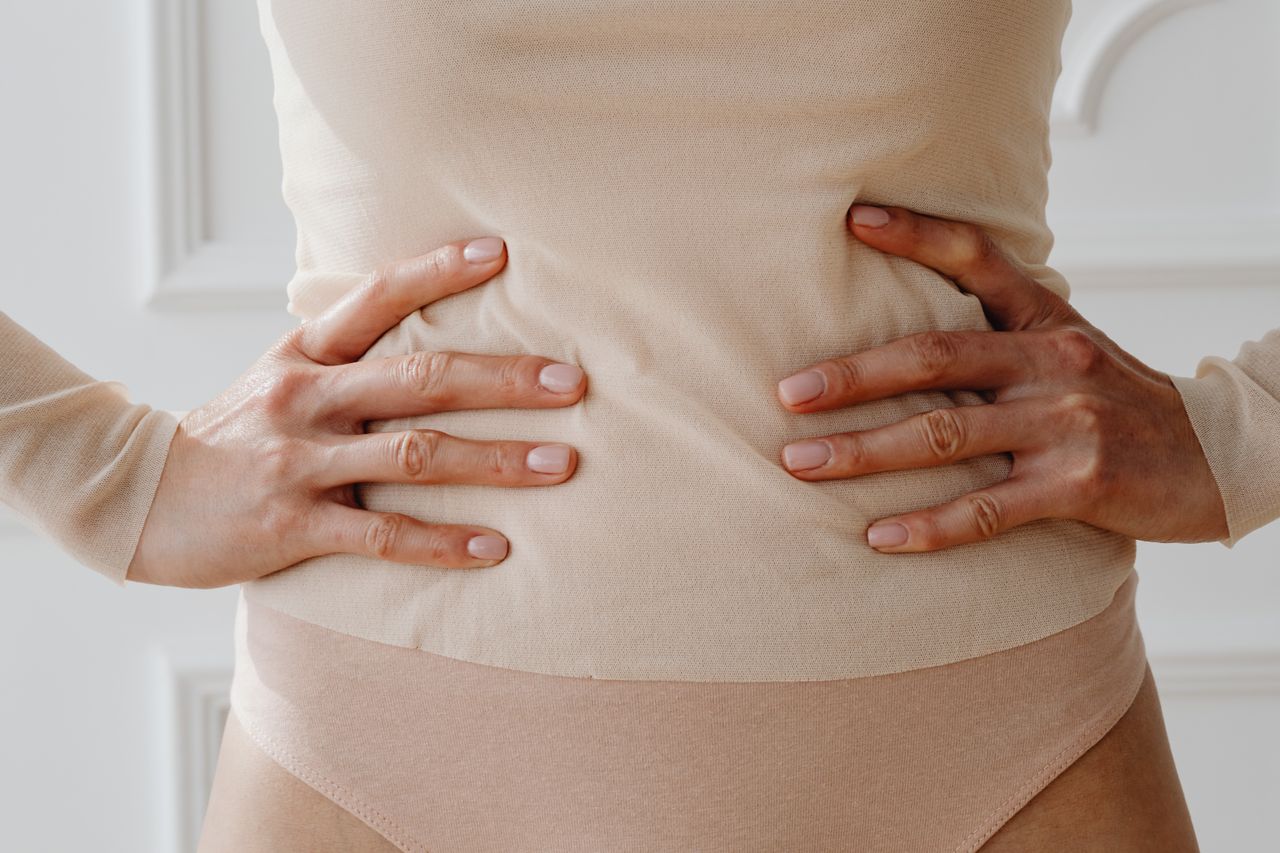 Žena se drži za struk obema rukama