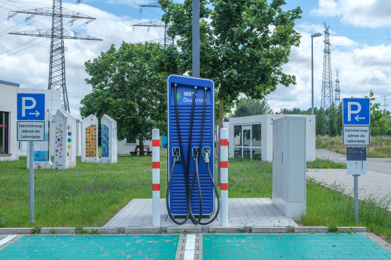 Plava stanica za punjenje električnih vozila sa kablovima i znakovima za parkiranje